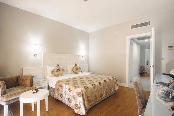 Schlafzimmer im Vita Silva Hotel mit Doppelbett, Nachttischen, Sesseln und offenen Türen.