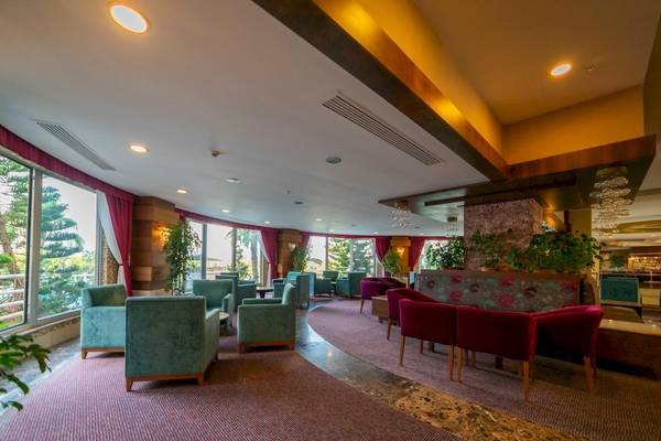Lobby-Lounge-Bereich des Vita Silva Hotels mit grünen und roten Sesseln und großen Fenstern.