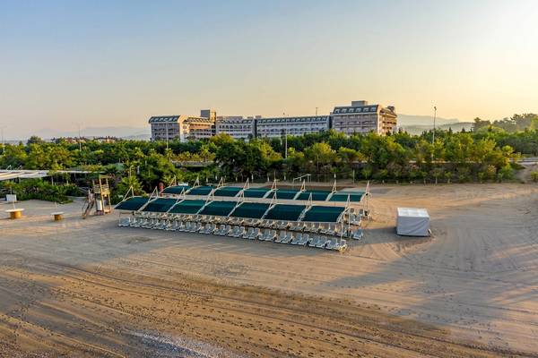 Luftaufnahme des Vita Silva Hotels mit einem Strand und grünen Sonnenschirmen.