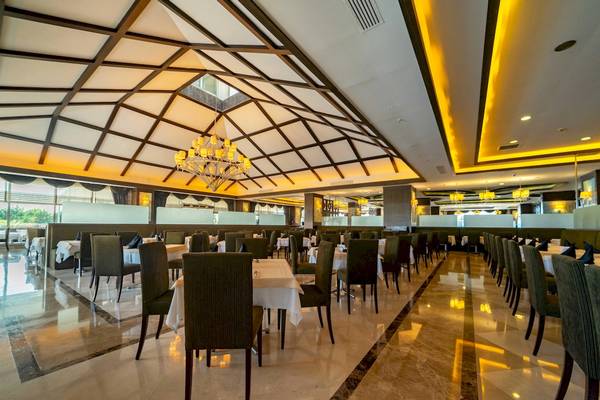 Innenansicht des Restaurants im Vita Silva Hotel mit geometrischen Decken, Tischen und Stühlen, goldenen Kronleuchtern und heller Beleuchtung.