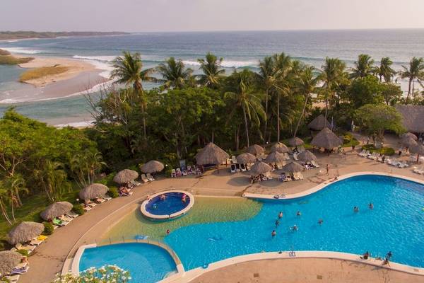 Luftaufnahme des Occidental Tamarindo Resorts mit Swimmingpool, Palmen und Meerblick.
