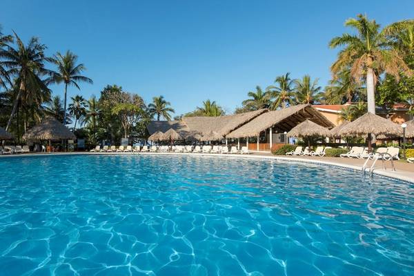 Außenpool des Occidental Tamarindo Hotels mit Sonnenliegen und Palmen