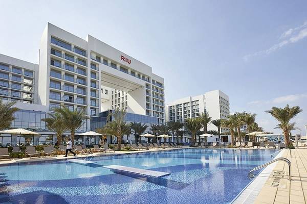Außenansicht des Riu Dubai Hotels mit Swimmingpool und Loungebereich.