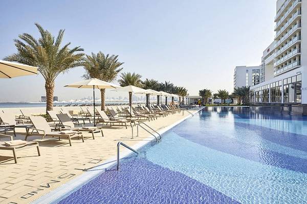 Außenpool des Riu Dubai Hotels mit Strand, Palmen und Liegestühlen