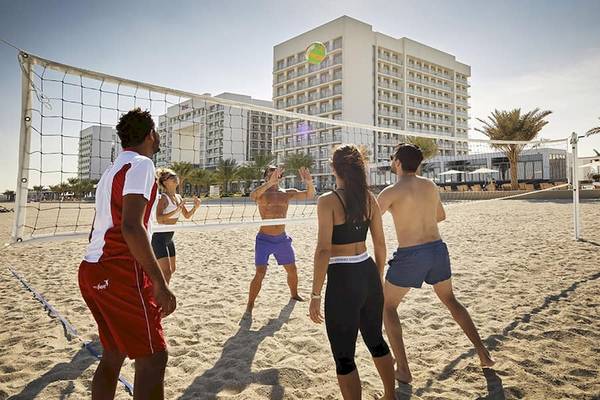 Gruppe spielt Volleyball am Strand vor dem Riu Dubai Hotel.
