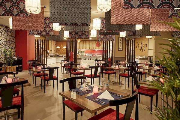 Innenraum des Riu Dubai Hotel Restaurants mit roten Stühlen und Tischdecken.