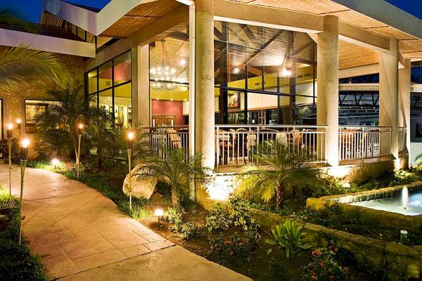 Abendliche Ansicht des Hotels Occidental Tamarindo mit beleuchtetem Gehweg und Terrasse.