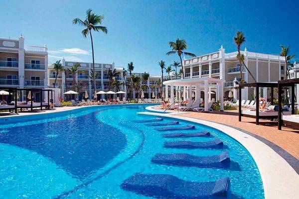 Außenpool des Riu Palace Bavaro Hotels mit Liegestühlen und Sonnenschirmen.