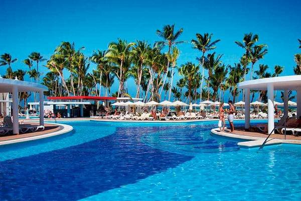 Außenpoolbereich des Riu Palace Bavaro Hotels mit Palmen und Sonnenliegen