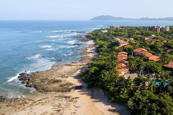 Außenansicht des Occidental Tamarindo Hotels mit Blick auf den Strand, das Meer und die Berge.