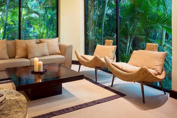 Wohnzimmer im Occidental Tamarindo Hotel mit Couch, Kerzen und Fenstern.