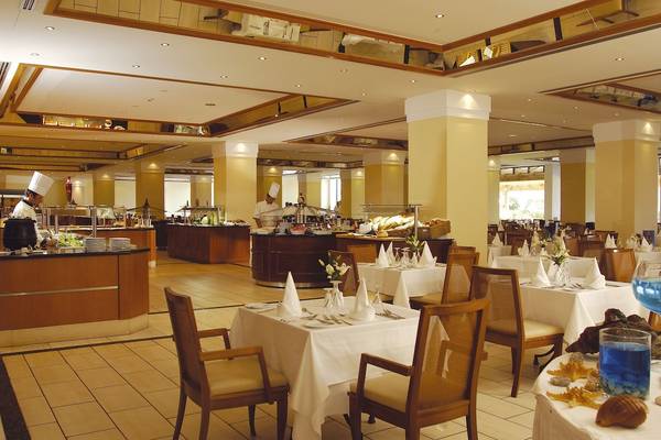 Innenbereich des Restaurants im Louis Kerkyra Blue Hotel mit besetzten Tischen und Bänken.