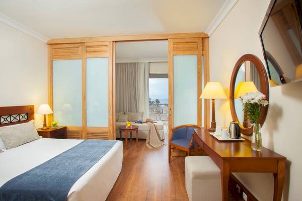 Innenansicht eines Hotelzimmers im Louis Kerkyra Blue mit Bett, Schreibtisch und Balkonzugang.