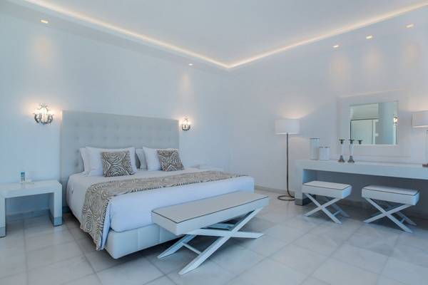 Schlafzimmer im DeLight Boutique Hotel mit weißen Möbeln und Bettwäsche, weißen Nachttischen und Stühlen.