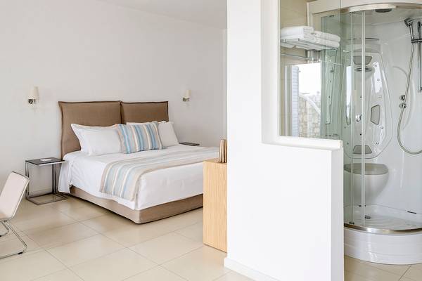 Schlafzimmer mit Bad im DeLight Boutique Hotel, zeigt ein Bett mit Kopfteil, Nachttisch und Dusche