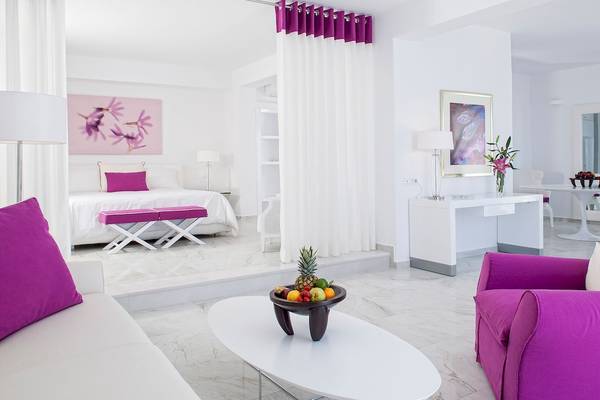 Innenansicht des DeLight Boutique Hotels mit weißem Schlafzimmer und Wohnzimmer mit violetten Akzenten.
