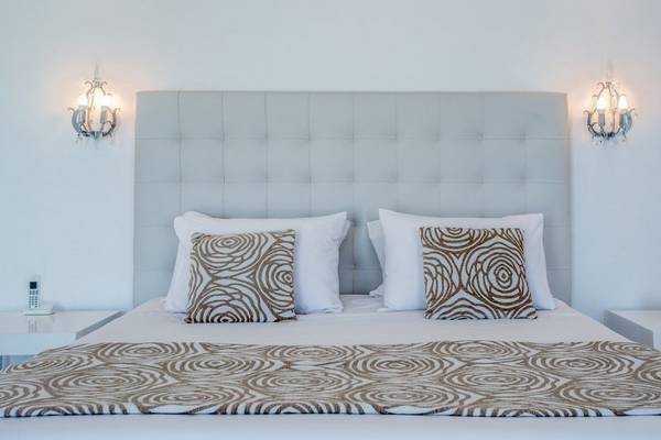 Bettzimmer im DeLight Boutique Hotel mit gemusterter Bettwäsche und weißen Kissen.