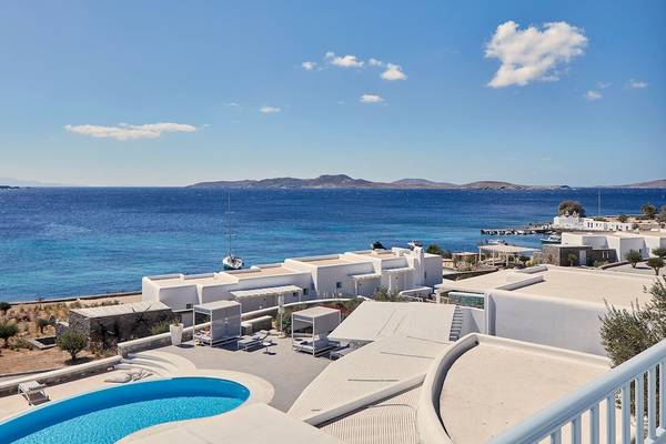 Aussicht auf das Meer vom DeLight Boutique Hotel mit weißen Gebäuden, Pool und Liegestühlen.