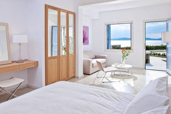 Innenansicht eines Zimmers im DeLight Boutique Hotel mit Bett, Spiegel, Lampe, Sessel und Fenstern.