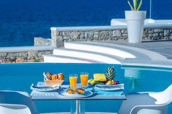 Frühstück am Pool im DeLight Boutique Hotel mit Meerblick, Obst, Croissants und Orangensaft.
