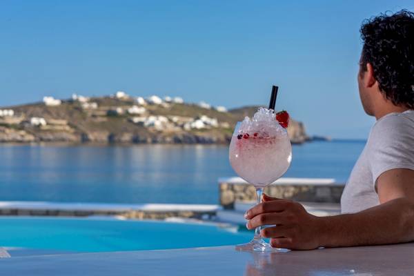 Mann mit einem rosa Cocktail am Pool mit Meerblick im DeLight Boutique Hotel.