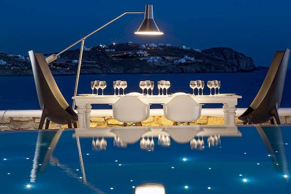 Außenbereich des DeLight Boutique Hotels mit Tisch und Stühlen am Pool bei Nacht