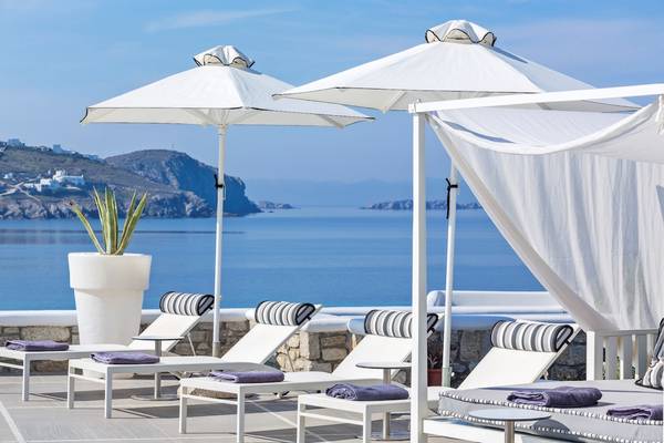 Terrasse des DeLight Boutique Hotels mit weißen Lounge-Stuhlen und Sonnenschirmen mit Blick auf das Meer.
