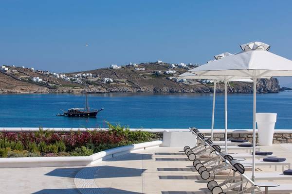 Terrasse des DeLight Boutique Hotels mit Sonnenliegen und weißen Sonnenschirmen.