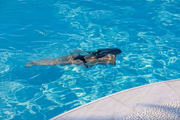 Eine Frau schwimmt in einem blauen Schwimmbad.