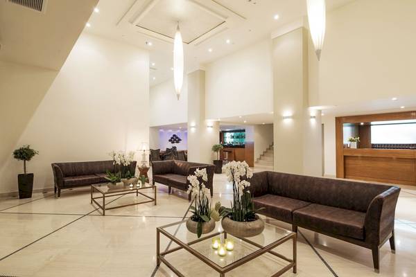 Lobbybereich des Mitsis La Vita Beach Hotels mit Sofas, Tischen und Pflanzen.