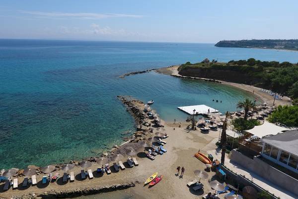 Luftaufnahme des Alexandra Beach Resorts & Spa mit Strand, Sonnenliegen, Sonnenschirmen und kristallklarem Wasser.