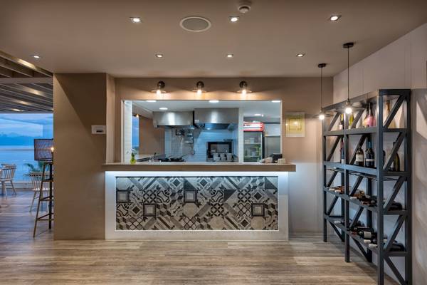 Innenbereich der Bar im Alexandra Beach Resort & Spa mit geometrischen Wandfliesen und Barschrank.