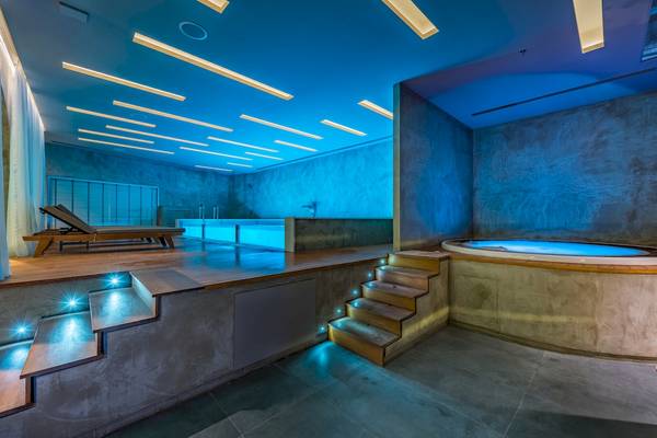 Innenbereich des Alexandra Beach Resort & Spa mit Poolbereich, beleuchteten Stufen und Liege.