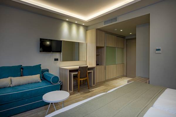 Zimmer im Alexandra Beach Resort & Spa mit blauem Sofa, Schreibtisch und Fernseher.