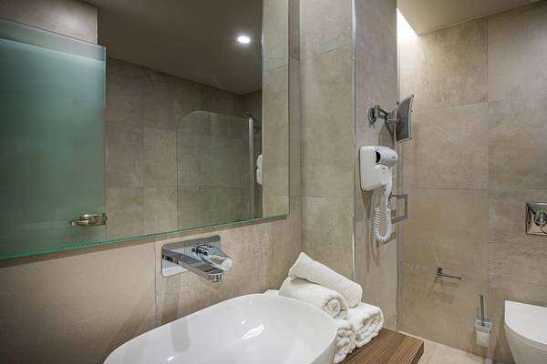 Badezimmer im Alexandra Beach Resort & Spa mit Waschbecken, Spiegel, Handtuchtrockner und Toilette.
