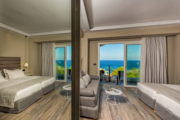 Hotelzimmer mit Meerblick im Alexandra Beach Resort & Spa, inklusive zwei Betten, Sofa und großer Glastür mit Balkon.