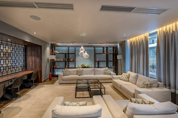 Wohnzimmer im Alexandra Beach Resort & Spa mit weißen Sofas, Glastisch und hängenden Lampen.