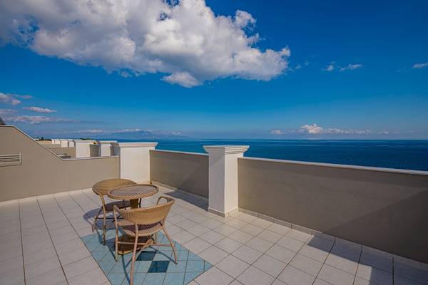 Terrasse mit Meerblick im Alexandra Beach Resort & Spa mit Tischen und Stühlen.