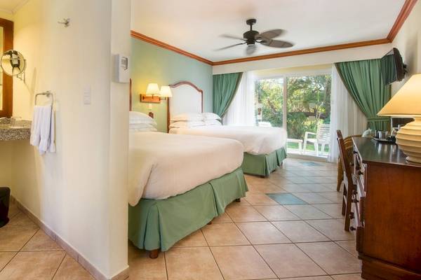 Hotelzimmer im Occidental Tamarindo mit zwei Betten, Badezimmerspiegel und Fenstern.