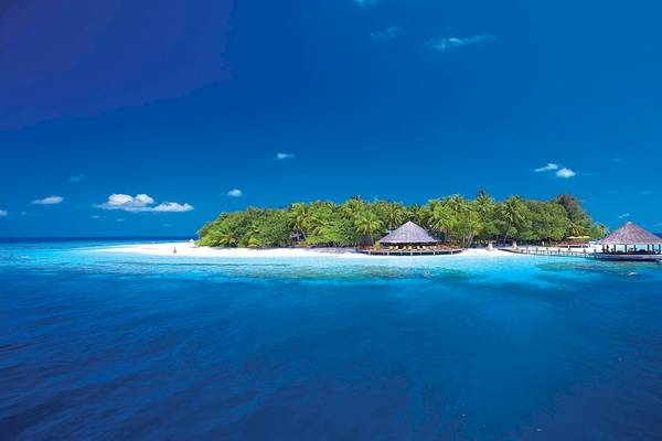 Außenansicht des Dhawa Ihuru Hotels, eine Insel mit weißen Stränden, grünen Bäumen und zwei runden Hütten.