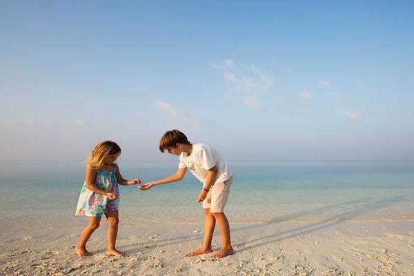 Zwei Kinder spielen am Strand des Dhawa Ihuru Hotels.