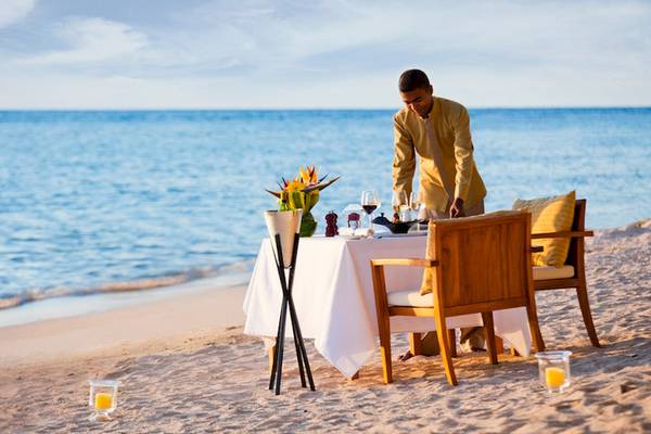 Ein Kellner bereitet ein Essen auf dem Strand am Dhawa Ihuru Hotel vor.