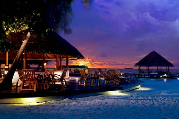 Dhawa Ihuru Hotel bei Abendstimmung am Strand mit beleuchteten Tischen und Stühlen