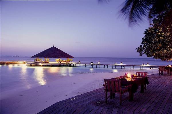 Abendessen am Strand im Dhawa Ihuru mit Blick auf das Meer und eine Hütte.