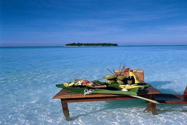 Tisch im Wasser mit Früchten und Flaschen im Dhawa Ihuru Hotel.