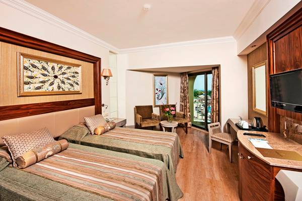Doppelzimmer im Side Star Resort mit zwei Betten, Schränken, Fernseher und Fenster mit Balkon.