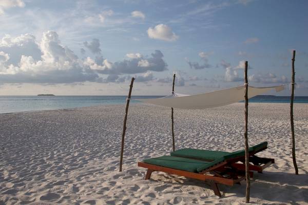 Strand des Coco Palm Dhuni Kolhu Hotels mit Sonnenliegen unter einem Segel