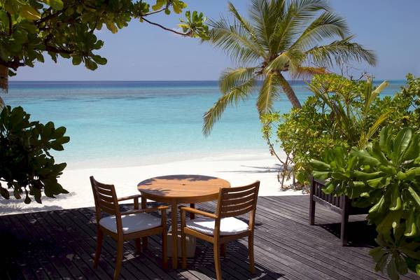 Terrasse mit Tisch und Stühlen am Strand im Coco Palm Dhuni Kolhu