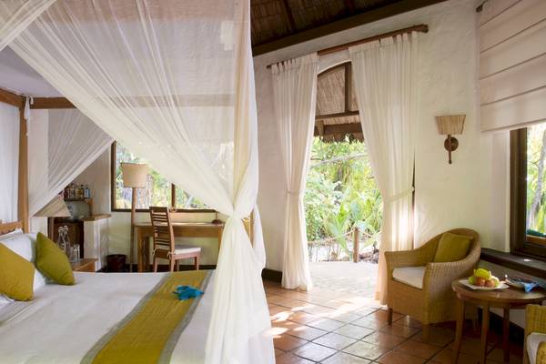 Schlafzimmer im Coco Palm Dhuni Kolhu Hotel mit Bett, Schreibtisch und Fenstern