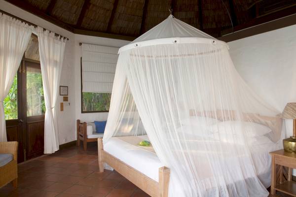 Ein Bett mit Moskitonetz im Coco Palm Dhuni Kolhu Hotelzimmer.